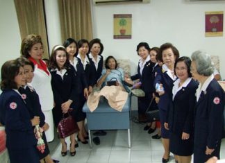 Red Cross members gather around to watch a benevolent person donate blood.